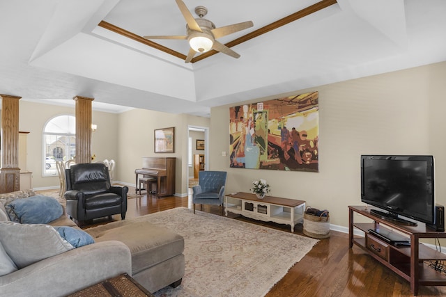 living room with decorative columns, a raised ceiling, dark wood-style floors, and a ceiling fan