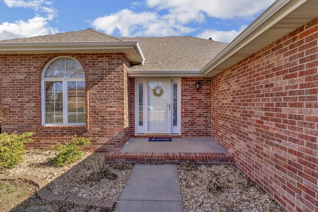 entrance to property with brick siding and roof with shingles