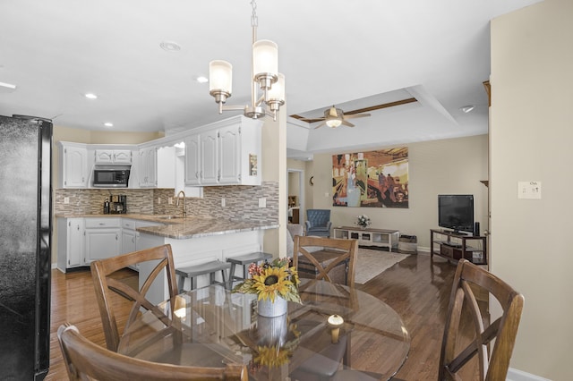 dining room featuring baseboards, a tray ceiling, recessed lighting, ceiling fan with notable chandelier, and wood finished floors