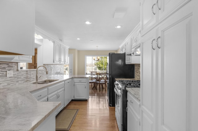 kitchen with wood finished floors, white cabinetry, stainless steel gas range, and a sink