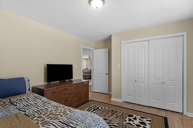 bedroom featuring a closet, light wood-style flooring, and baseboards