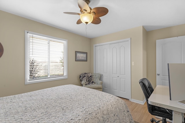 bedroom with a closet, light wood-style flooring, a ceiling fan, and baseboards