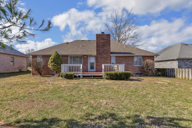 rear view of property with fence, a wooden deck, a chimney, a lawn, and brick siding