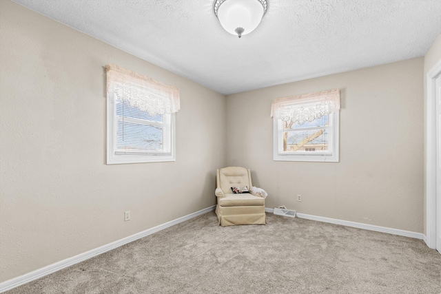 unfurnished room featuring visible vents, plenty of natural light, a textured ceiling, and carpet flooring