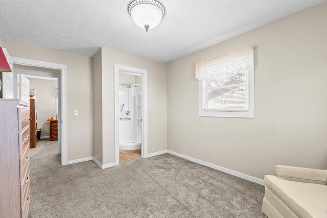 bedroom featuring ensuite bath, carpet, baseboards, and a textured ceiling