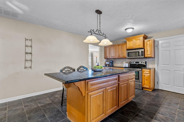 kitchen featuring a kitchen island, a breakfast bar, dark stone counters, appliances with stainless steel finishes, and backsplash