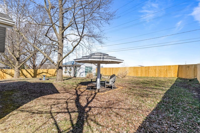 view of yard with an outdoor structure, a fenced backyard, and an outdoor fire pit