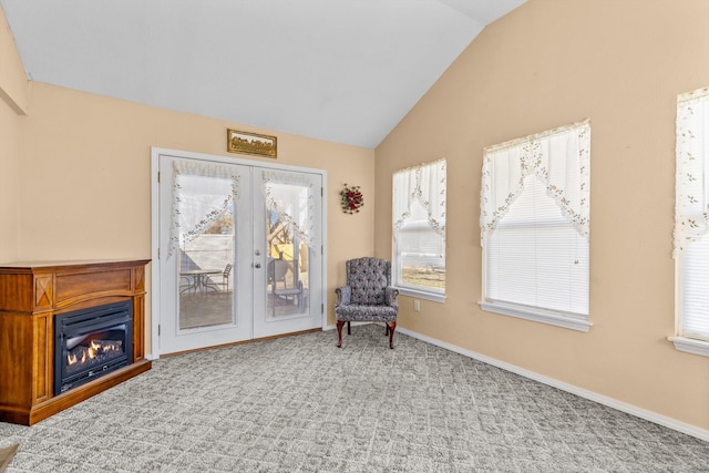 living area featuring baseboards, lofted ceiling, carpet flooring, french doors, and a glass covered fireplace