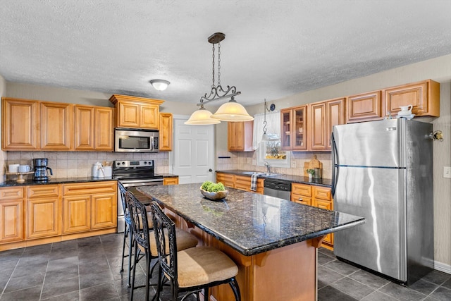 kitchen with a kitchen breakfast bar, tasteful backsplash, a kitchen island, stainless steel appliances, and glass insert cabinets