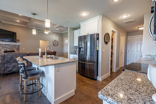 kitchen with dark wood-type flooring, a sink, open floor plan, stainless steel fridge with ice dispenser, and a brick fireplace