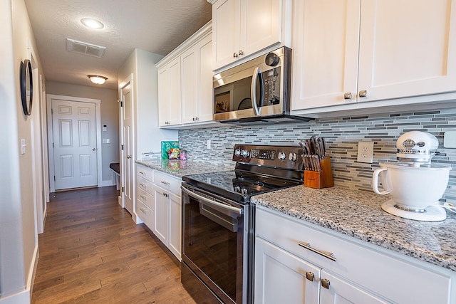 kitchen featuring visible vents, dark wood finished floors, appliances with stainless steel finishes, white cabinets, and decorative backsplash