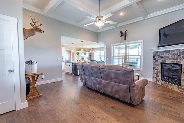 living room with a brick fireplace, dark wood-type flooring, baseboards, crown molding, and coffered ceiling