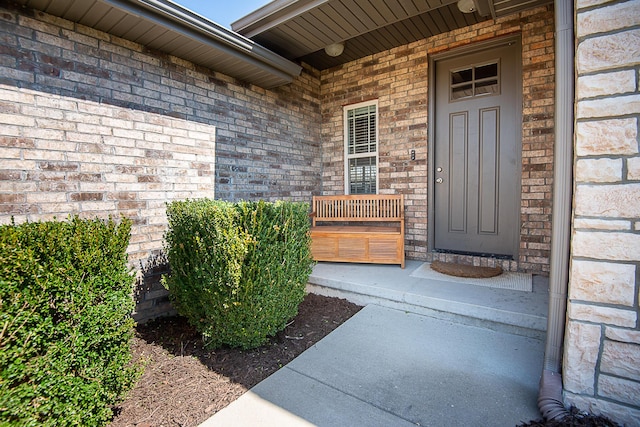 view of exterior entry with brick siding and a porch