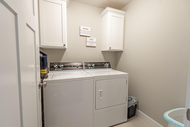 laundry room with washer and clothes dryer, cabinet space, and baseboards