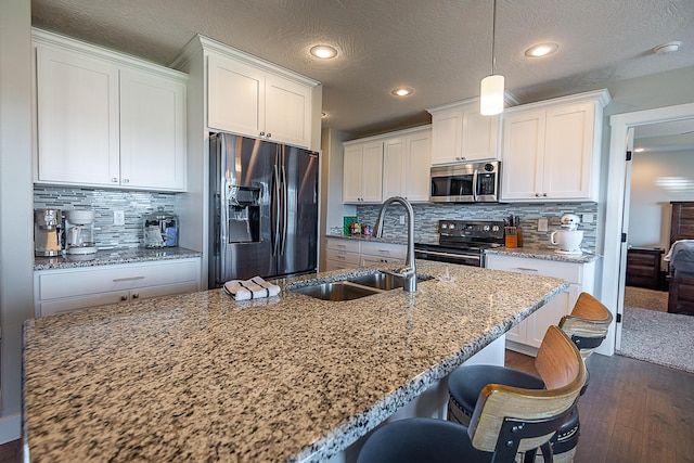 kitchen featuring dark wood-style floors, white cabinets, appliances with stainless steel finishes, and a sink