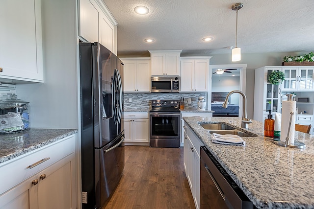 kitchen featuring tasteful backsplash, appliances with stainless steel finishes, dark wood-style floors, white cabinetry, and a sink