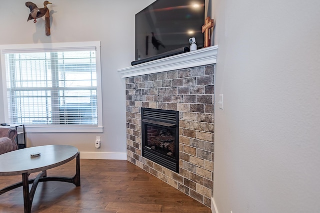 living room with baseboards, a brick fireplace, dark wood-style flooring, and a healthy amount of sunlight