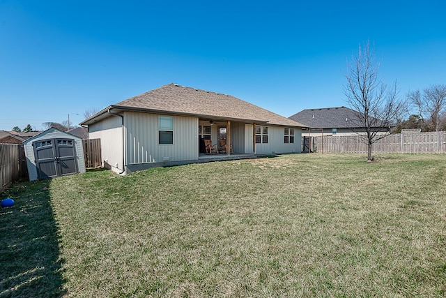 rear view of property with a lawn, a fenced backyard, a shed, an outdoor structure, and ceiling fan