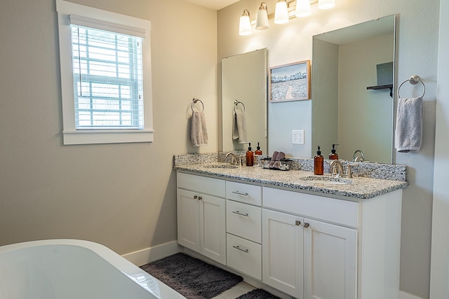 bathroom with a sink, baseboards, a freestanding bath, and double vanity