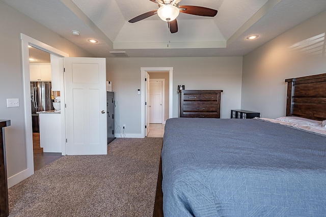 bedroom with a tray ceiling, freestanding refrigerator, recessed lighting, carpet flooring, and baseboards