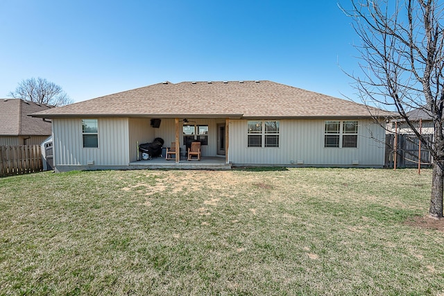 rear view of house with a shingled roof, ceiling fan, fence, a lawn, and a patio area