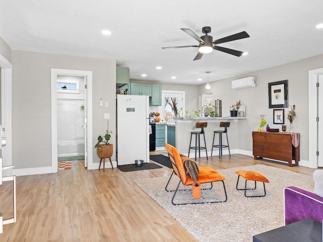 living area with recessed lighting, baseboards, light wood-style flooring, and a wall unit AC