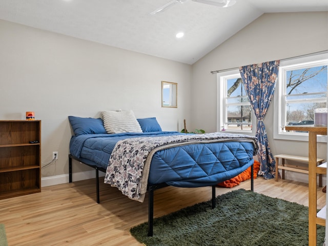 bedroom with vaulted ceiling, light wood-style flooring, and baseboards