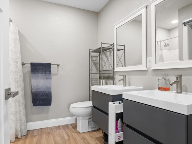 full bathroom with toilet, two vanities, baseboards, and wood finished floors