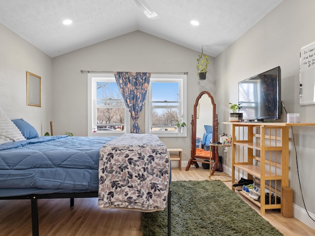 bedroom featuring lofted ceiling, wood finished floors, and baseboards