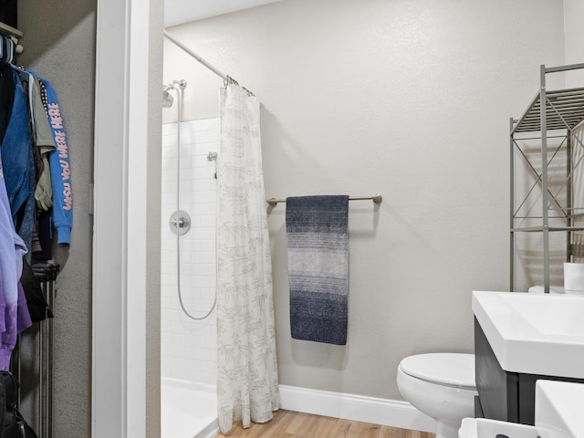 bathroom featuring a shower stall, toilet, baseboards, and wood finished floors