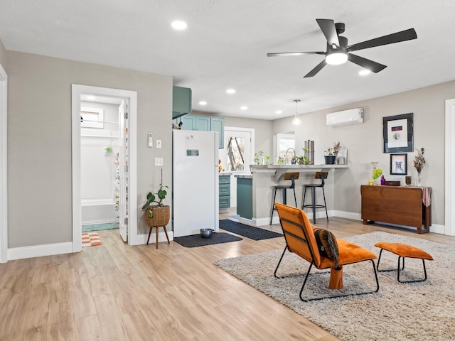 living room featuring a wall unit AC, recessed lighting, baseboards, and light wood finished floors