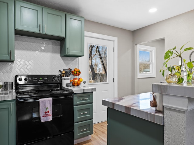 kitchen featuring green cabinetry, black / electric stove, and backsplash