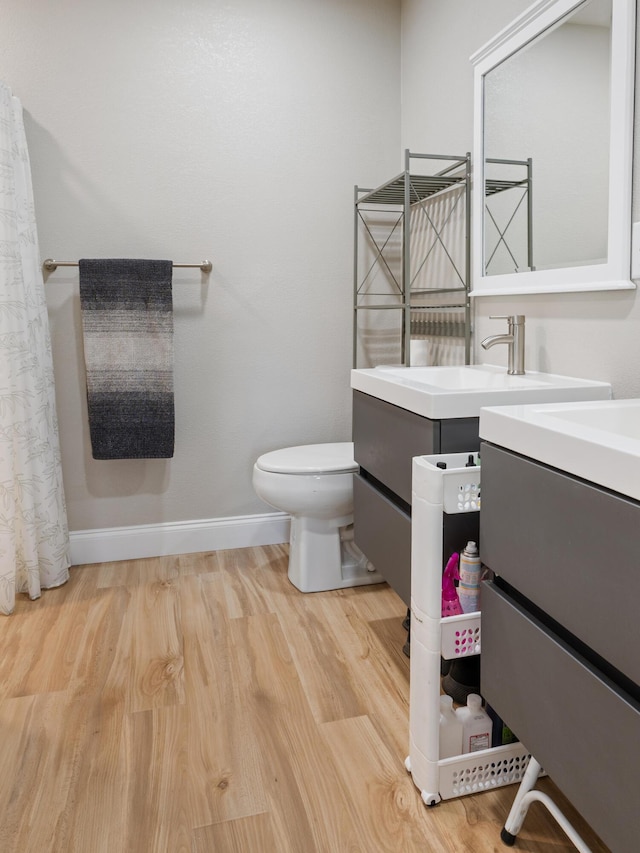 full bath with toilet, vanity, baseboards, and wood finished floors