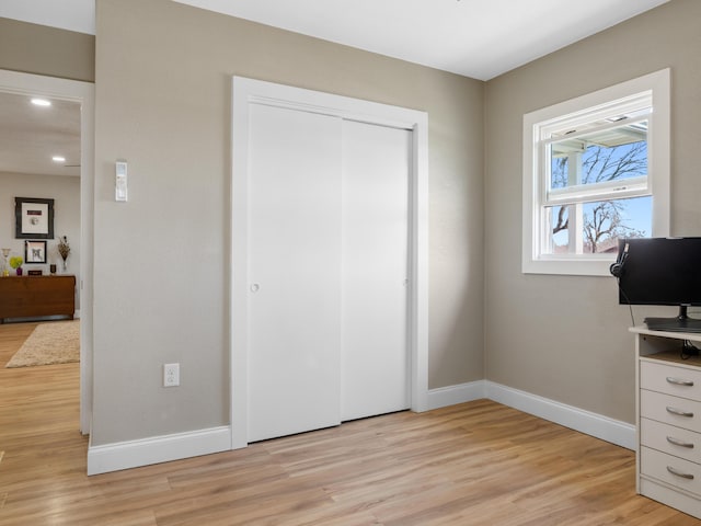 unfurnished bedroom with a closet, baseboards, and light wood-style floors