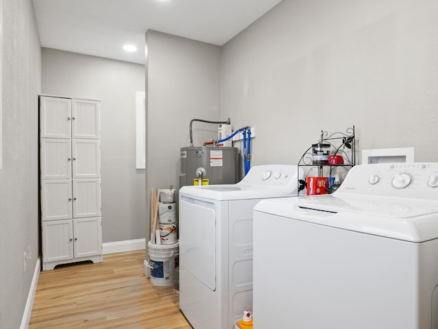 laundry area with baseboards, washer and clothes dryer, light wood-type flooring, water heater, and cabinet space