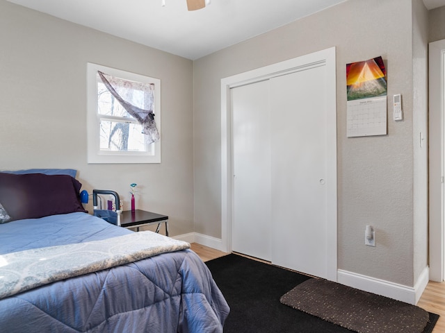 bedroom featuring a closet, ceiling fan, baseboards, and light wood-style floors