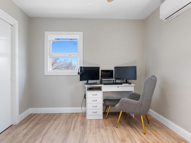 home office featuring ceiling fan, baseboards, light wood-type flooring, and a wall unit AC