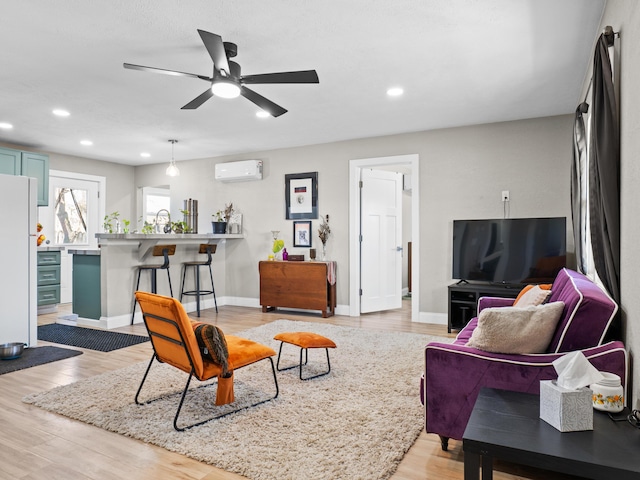 living area with recessed lighting, baseboards, light wood-style floors, and a wall unit AC