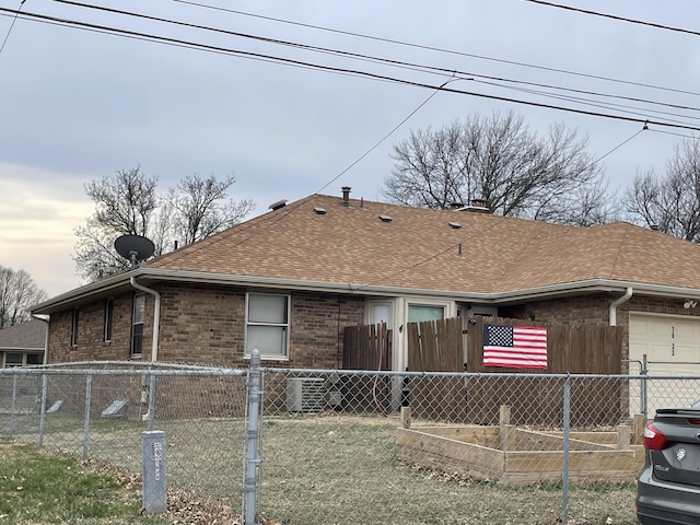 rear view of house featuring a garage, fence, brick siding, and a shingled roof