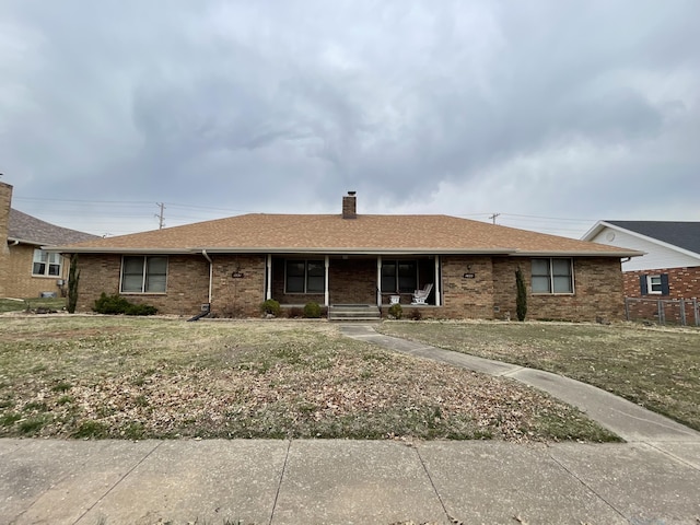 single story home with brick siding, a porch, a chimney, and roof with shingles