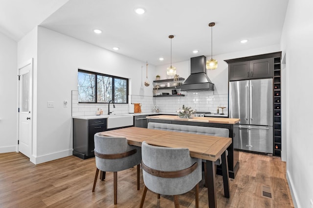 kitchen featuring custom range hood, light wood-style floors, appliances with stainless steel finishes, and a sink