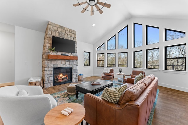 living area featuring a fireplace, plenty of natural light, wood finished floors, and high vaulted ceiling