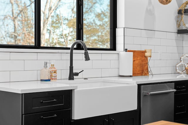 kitchen featuring a sink, tasteful backsplash, dark cabinetry, and light countertops