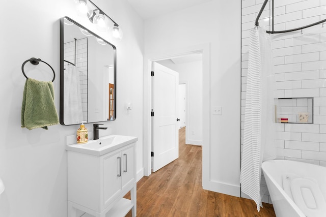 bathroom with shower / bathtub combination with curtain, vanity, baseboards, and wood finished floors