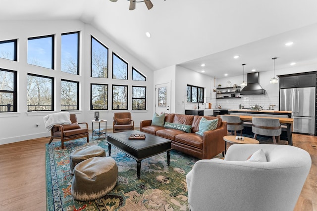 living area featuring high vaulted ceiling, a ceiling fan, recessed lighting, light wood-style floors, and baseboards