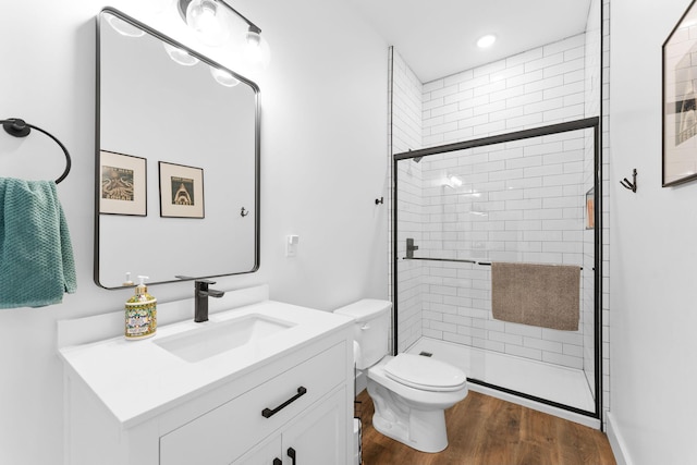 full bathroom featuring vanity, toilet, wood finished floors, and a stall shower