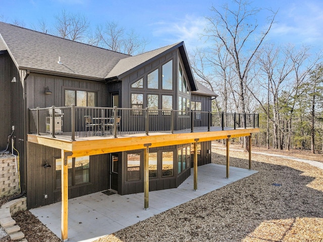 back of property featuring board and batten siding, roof with shingles, and a patio area