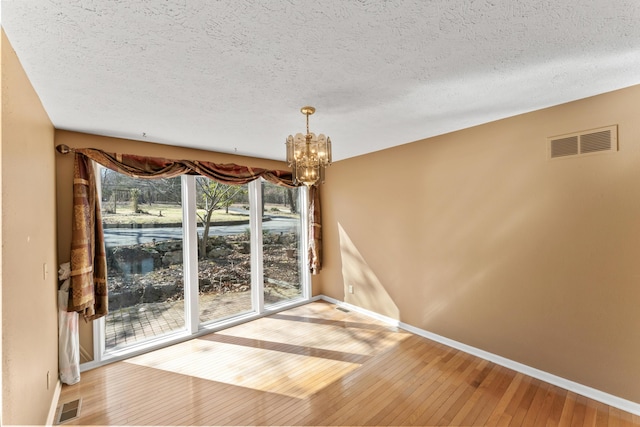25906 Farm Rd Unit 1263, Golden, MO 65658 - unfurnished dining area featuring visible vents, baseboards, an inviting chandelier, and hardwood / wood-style flooring