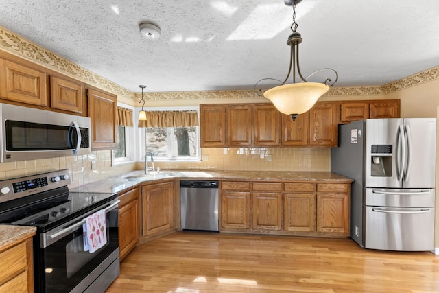 25906 Farm Rd Unit 1263, Golden, MO 65658 - kitchen with brown cabinets, pendant lighting, a sink, light wood-style floors, and appliances with stainless steel finishes
