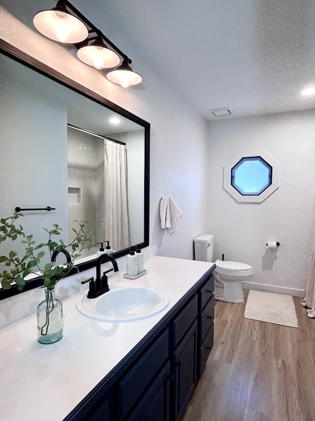 full bath with vanity, a shower with shower curtain, wood finished floors, a textured ceiling, and toilet